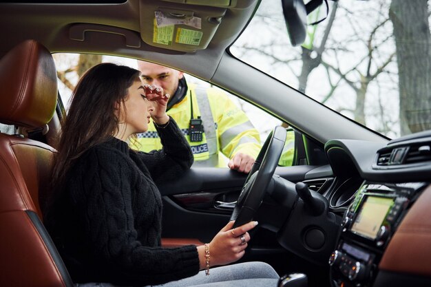 Meisjes voelen zich slecht. Mannelijke politieagent in groen uniform die voertuig op de weg controleert.