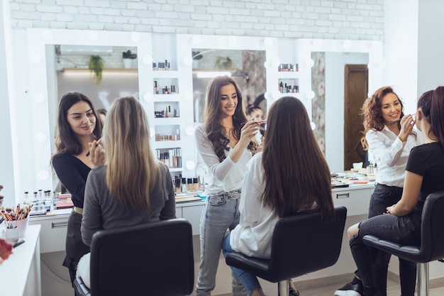 Meisjes volgen de make-up masterclass. Ze trainen op het model hoe ze perfecte make-up kunnen doen.