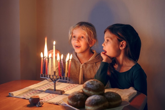 Meisjes vrienden die kaarsen aansteken op de menorah voor de traditionele winter Joodse Hanukkah vakantie thuis