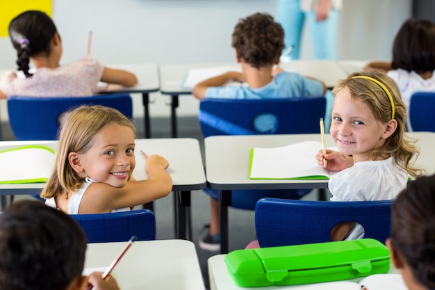 Meisjes zitten met klasgenoten in de klas