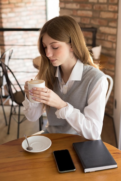 Meisjesblogger drinkt 's ochtends cappuccino in een coffeeshop