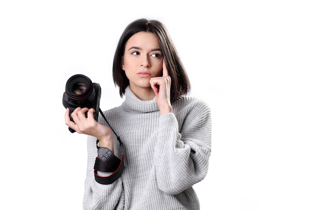 meisjesfotograaf die moderne camera gebruikt die bedachtzaam opzij kijkt en verbaasd is