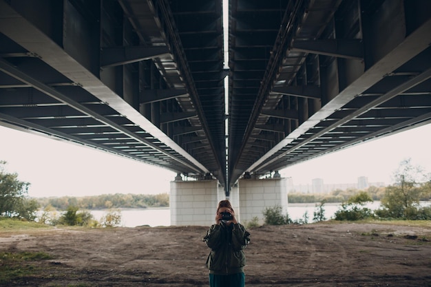 Meisjesfotograaf met een camera onder de brug