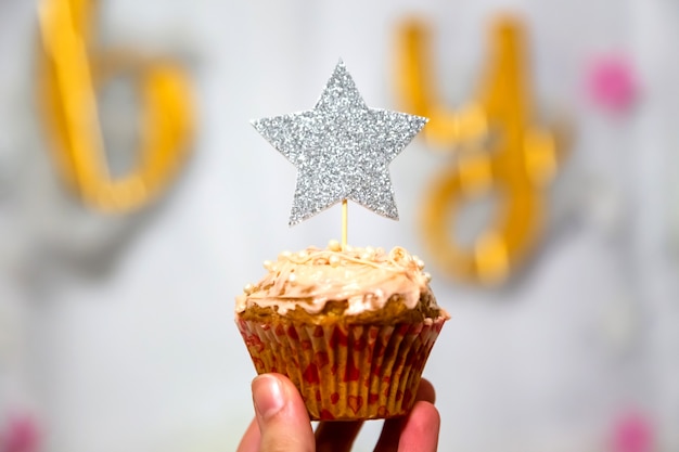 Meisjeshand houdt cranberry cupcake met zilveren glitter ster topper