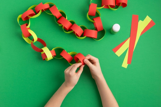 Foto meisjeshanden maken papieren ketting voor het nieuwe jaar kerstversiering dyi gemakkelijke bezigheid thuis hoog