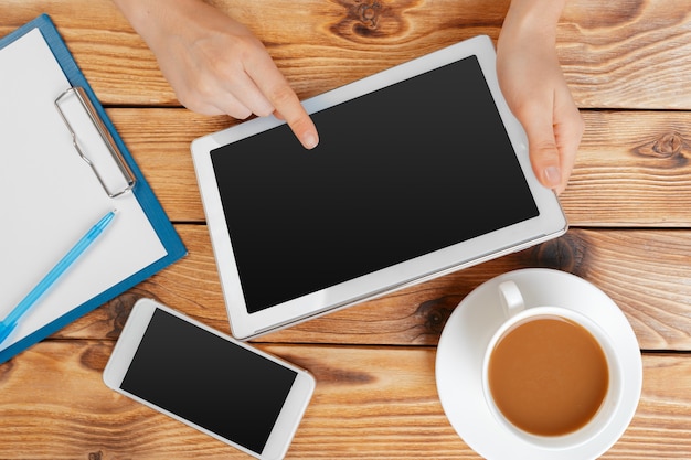 Meisjeshanden met digitale tablet en kopje koffie op een houten tafel