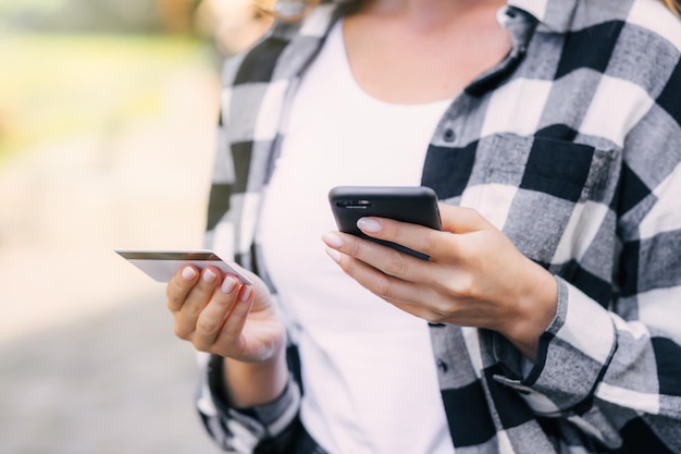 Meisjeshanden met een creditcard en mobiele telefoon op straat Online winkelconcept