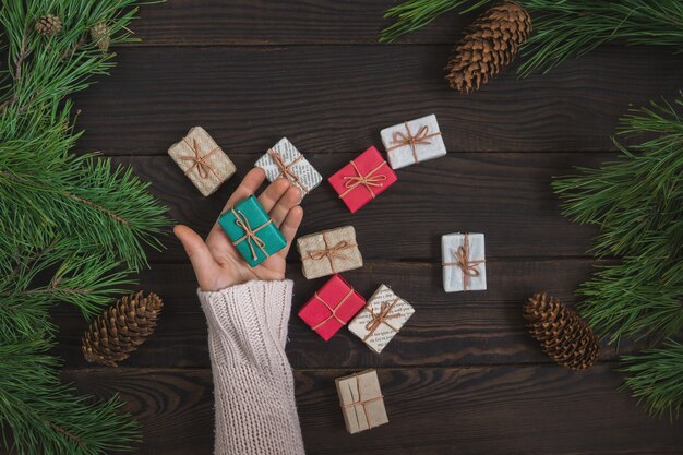 Meisjeshanden met kerstcadeau op de achtergrond van donkere planken van pijnboomtakken