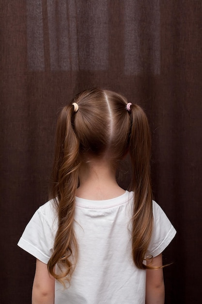 Meisjeskapsel gevlochten in een vlecht gefixeerd met een blauwe elastische band close-up Haarstyling gebeurt met haarspelden en een elastische band Alleen de achterkant van het hoofd met een knipbeurt