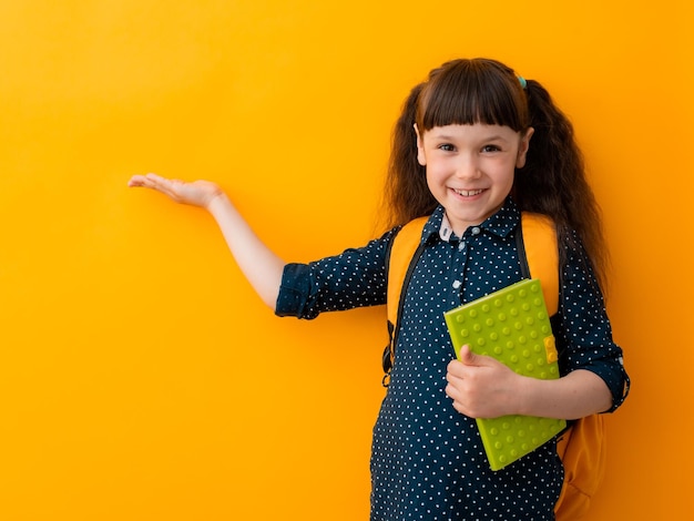 Meisjeskind is een schoolmeisje met een rugzak met een reclameobject gemarkeerd op een helderblauwe achtergrond