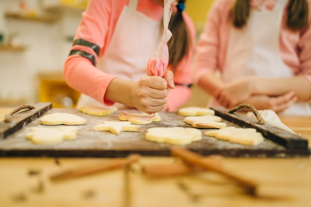 Meisjeskoks bereiden zich voor om koekjes in de oven te sturen