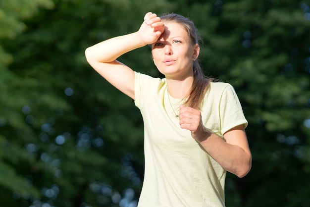 Meisjesloper lijdt aan pijn bij hardlopen, joggen. Hitte, vrouw met zonnesteek. Zonnesteek hebben bij warm zomerweer. Gevaarlijke zon, meisje onder de zon. Hoofdpijn, zich slecht voelen, moe, uitgeput