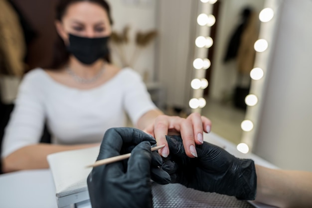 Meisjesmeester van manicure maakt een manicure voor een klant met behulp van een bamboestok Schoonheidssalon manicure nagelpolijstprocedure