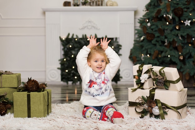 Meisjespelen met denneappelsdecoratie aan de Kerstboom.