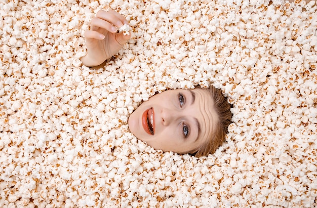 Meisjesportret in popcorn. Jonge vrouw begraven in popcorn.