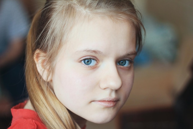 Meisjestiener thuis - het portret van een wijfje van blonde haarblauwe ogen, sluit omhoog