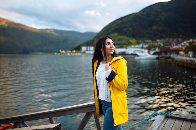 Meisjestoerist in gele jas die zich voordeed op het meer in Noorwegen Actieve vrouw die ontspant in Noorwegen