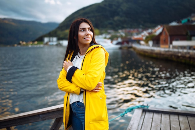 Meisjestoerist in gele jas die zich voordeed op het meer in Noorwegen Actieve vrouw die ontspant in Noorwegen