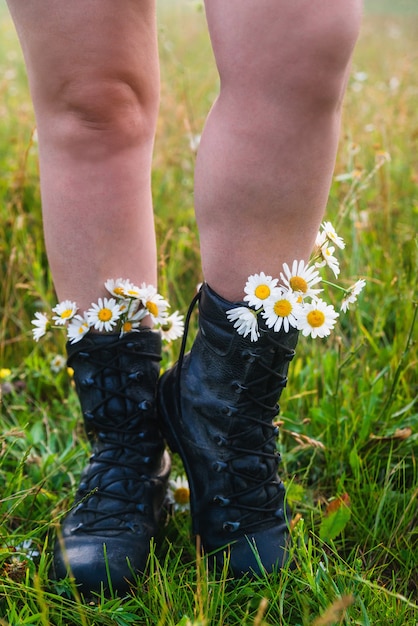 Meisjestoerist in laarzen met madeliefjes. Wandelschoenen close-up.