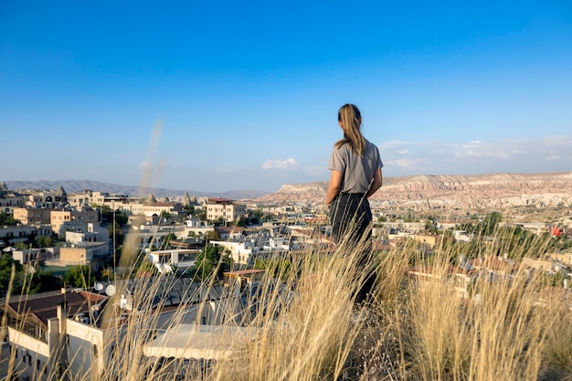 Meisjestoerist kijkt naar de horizon in Goreme Cappadoci Toeristenstad met huizen in Cappadocië