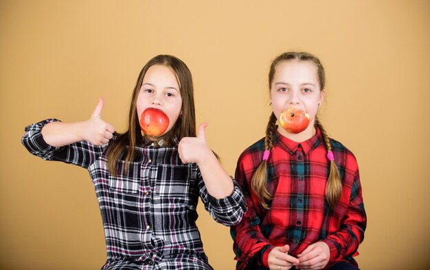 Meisjesvrienden eten appelsnack terwijl ze ontspannen Schoolsnackconcept Tieners met gezonde snack Vrolijke kinderen die plezier hebben en appels eten We hebben een gezond dieet Gezond dieet en vitaminevoeding