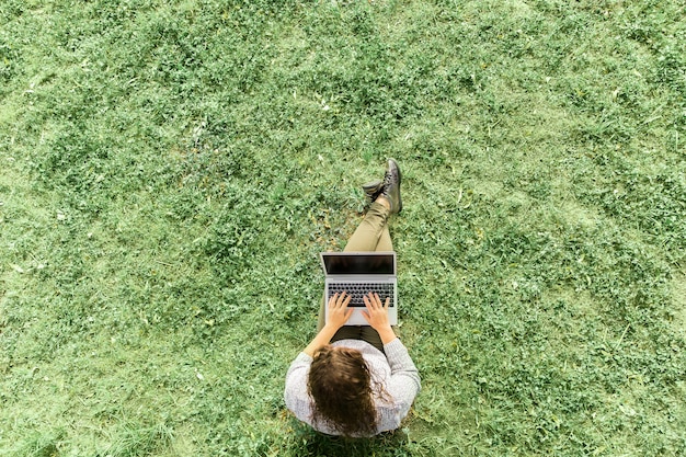 Meisjeszitting met notitieboekje op gras in een park