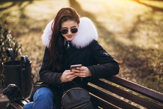 Meisjeszitting op een bank en het spreken op de telefoon