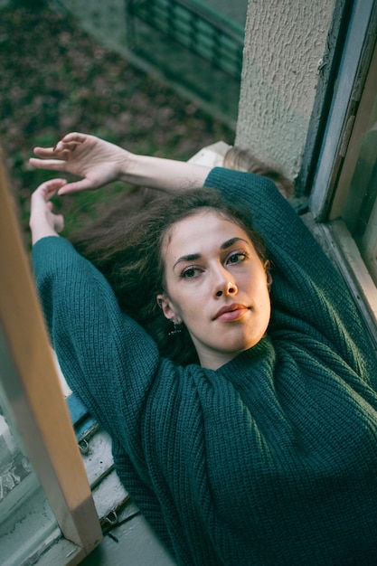 Melancholisch portret van een gracieus meisje met een sensueel gezicht op de vensterbank als in een filmfoto.