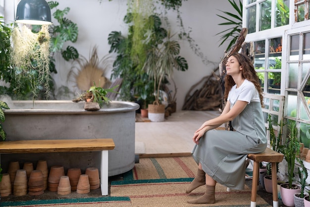 Melancholische tuinman vrouw rust na het werk in bloemenwinkel of kas Geestelijke gezondheidsconcept