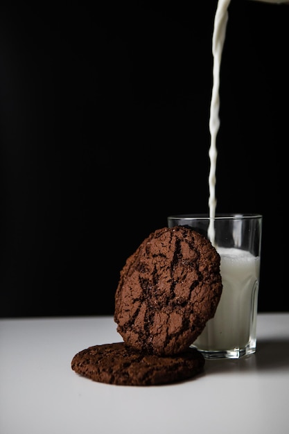 Melk gieten in glas met chocoladekoekjes