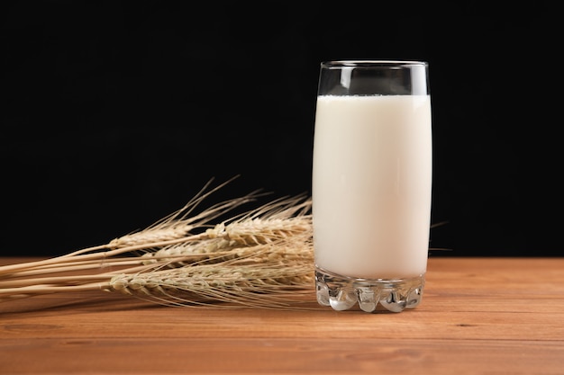 Melk in een glas en tarwe op een houten tafel