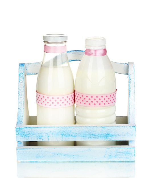Foto melk in flessen in houten doos die op wit wordt geïsoleerd