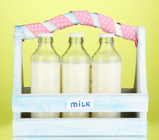 Foto melk in flessen in houten kist op groene achtergrond