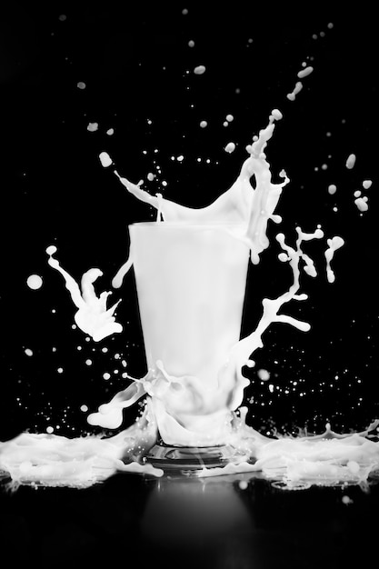 Melk splash met glas op zwart