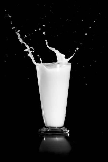 Melk splash met glas op zwart