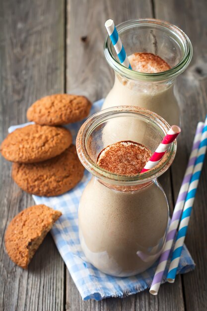 Melk vanille smoothies met havermoutkoekjes in glazen potten op de oude houten