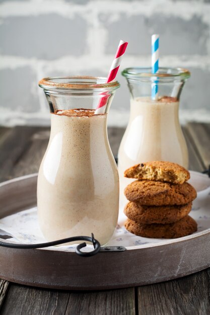 Melk vanille smoothies met havermoutkoekjes in glazen potten op het oude houten oppervlak. Selectieve aandacht.