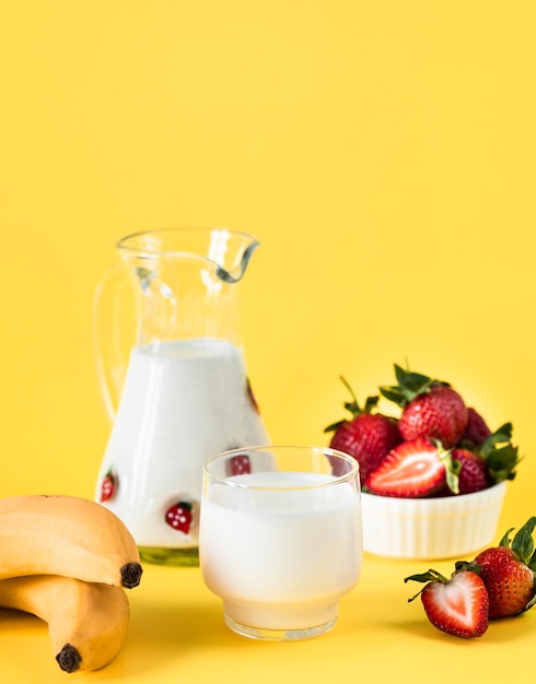 Melk verse aardbeien en bananen op een gele achtergrond gezonde voeding en voeding levensstijl