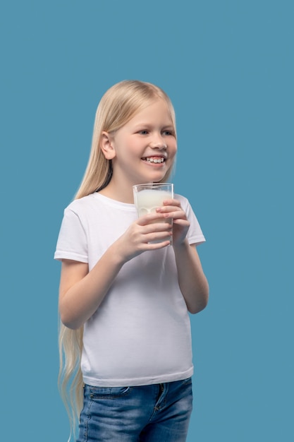Melk voor de gezondheid. glimlachend mooi meisje met lang blond haar dat een glas melk in haar handen houdt