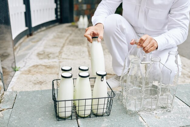 Melkboer glazen melkflessen in draadkraan zetten en lege flessen terugnemen