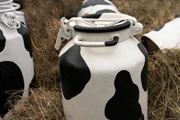 Melkbus is geverfd met witte en zwarte vlekken een container voor het verzamelen en opslaan van melk tegen de achtergrond van droog gras stro installatie selectieve focus