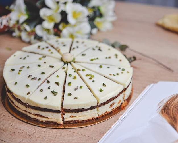 melkcake met amandeltopping op een houten tafel met bloemen rond close-up