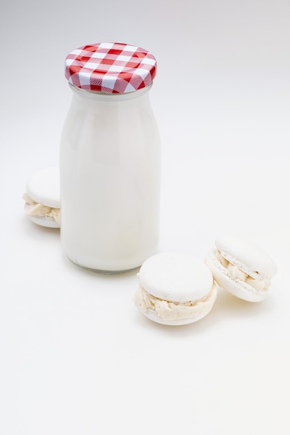 Melkfles met heerlijke witte macarons. Kopieer ruimte. Geïsoleerd.