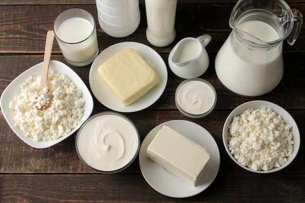 Melkproducten. Melk, zure room, kaas, boter en kwark op een bruin houten tafel. bovenaanzicht