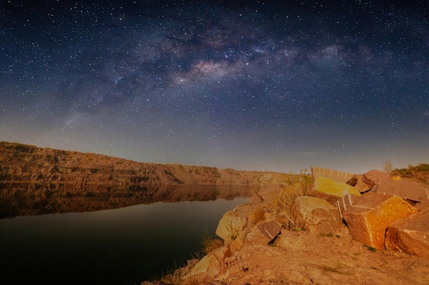 Melkweg over een meer in een granietgroeve 's nachts Zomerlandschap met enorme rotsblokken bomen paarse lucht met Melkweg en sterren prachtige reflectie in het water Oekraïne Ruimte en natuur