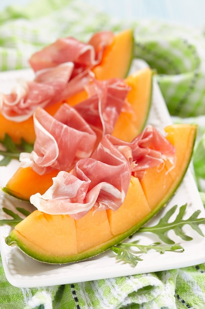 Foto melone e prosciutto su un piatto bianco