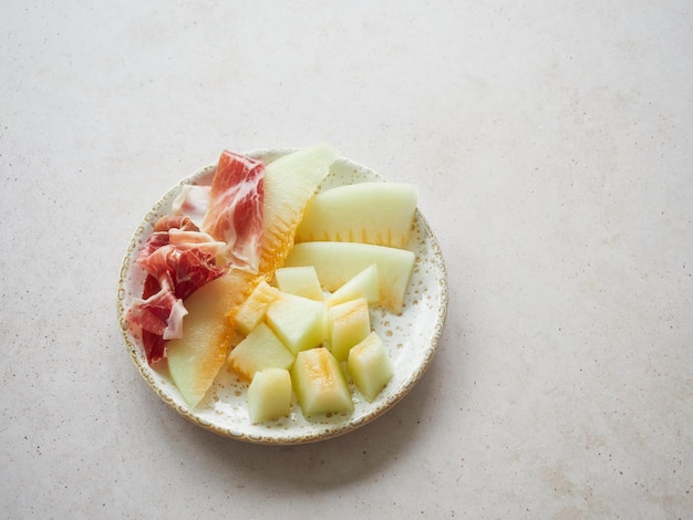 Melon with ham on a plate Typical spanish tapa Contrast sweet salty flavor