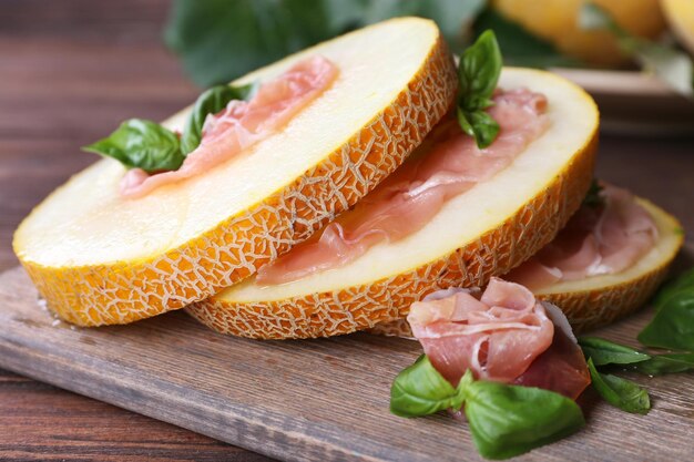 Melon with prosciutto of Parma ham on wooden table closeup