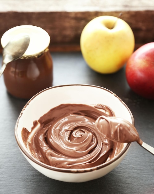 Melted chocolate in bowl on wooden background