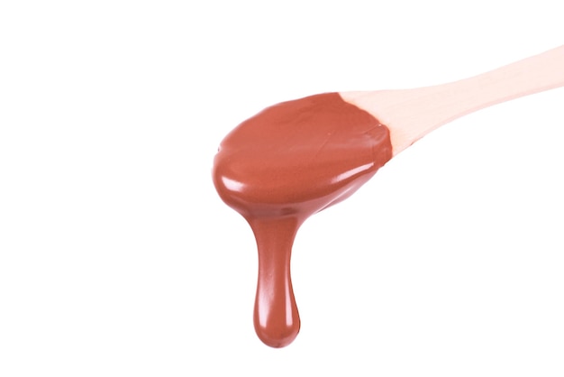 Melted dark chocolate dripping of wooden spoon on white background